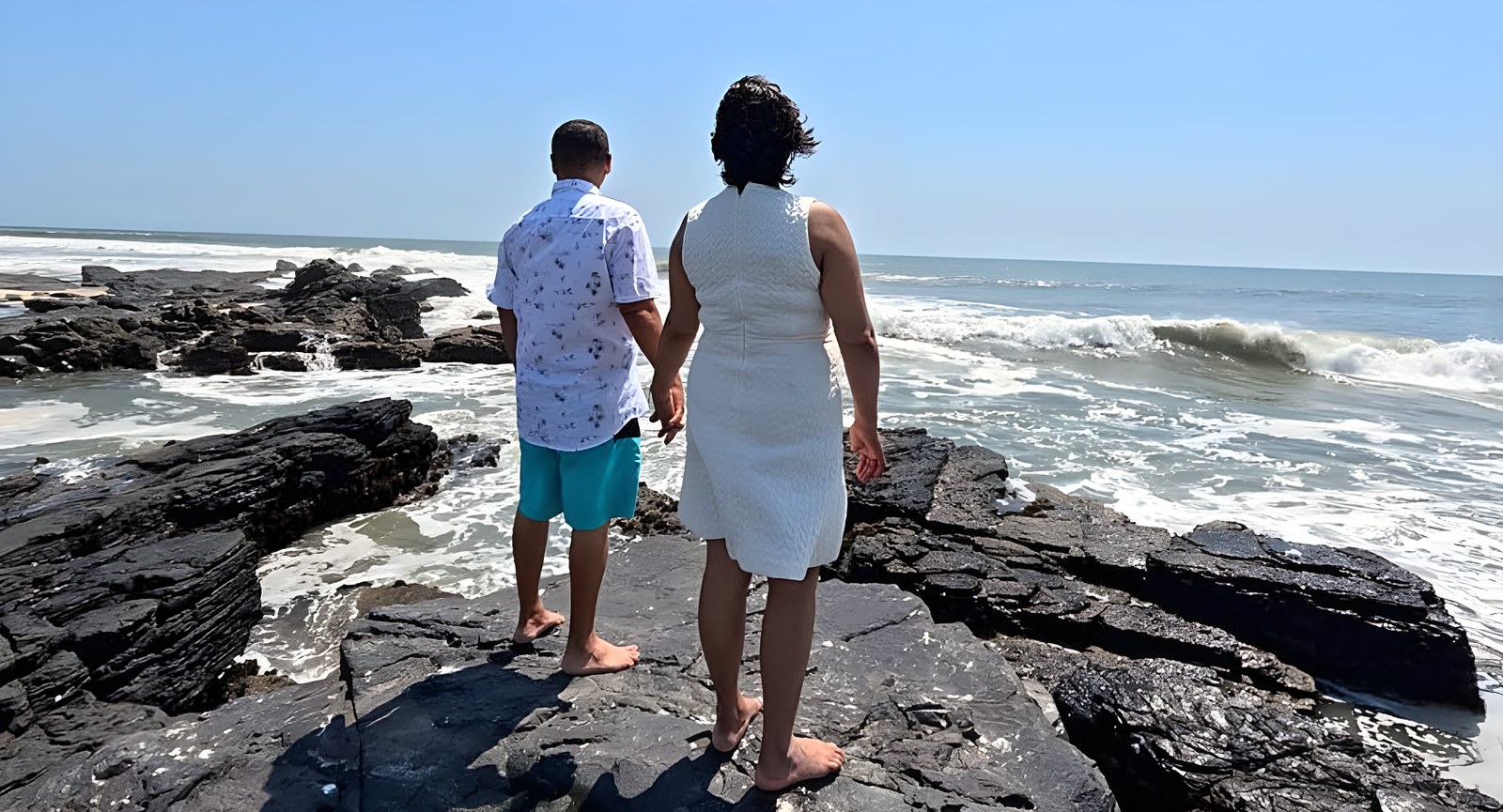 De espaldas, tomados de la mano mirando el mar