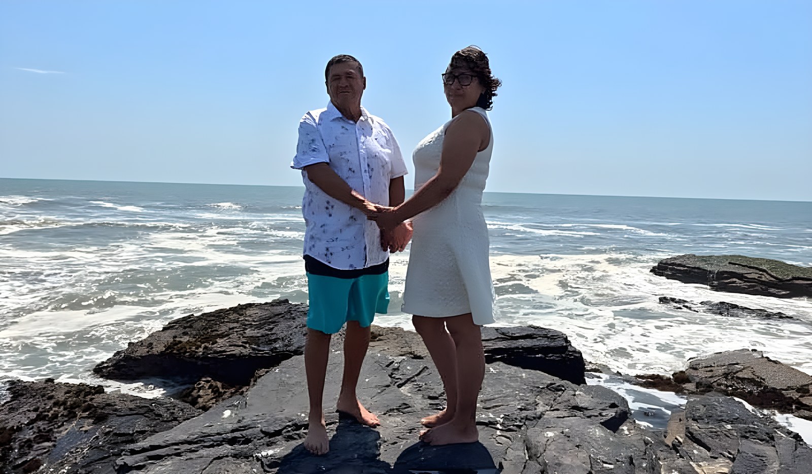 Arturo y Aracelita tomados de la mano sobre las rocas, frente al mar